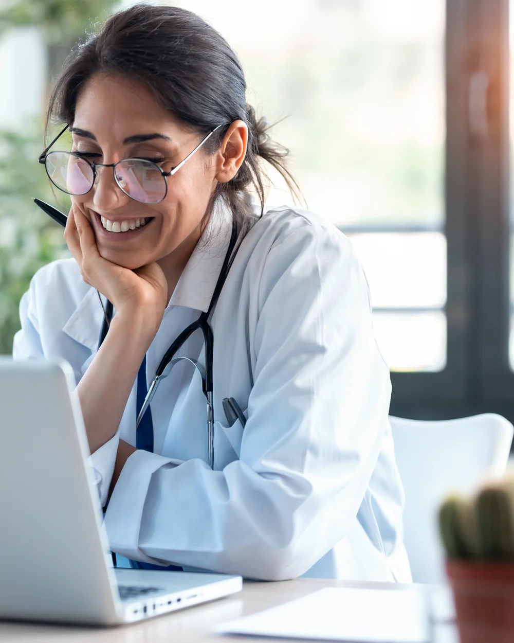 A physician smiling at her laptop