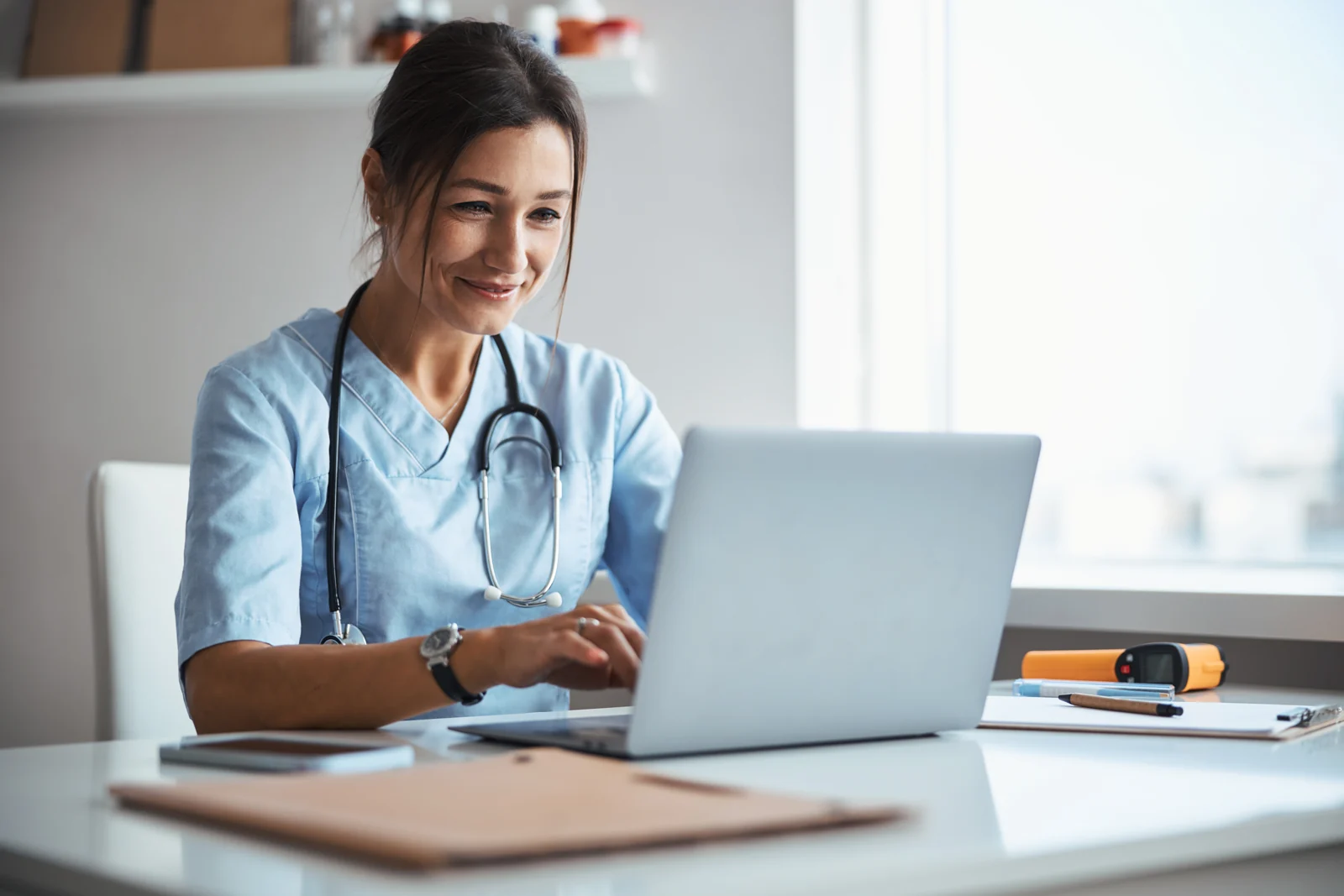 A research coordinator reviewing referrals at a laptop